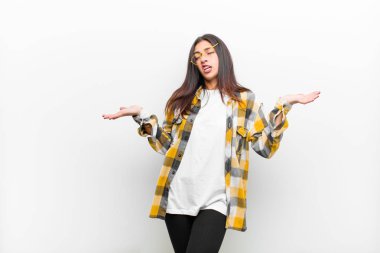 Genç, güzel bir kadın aptal, deli, kafası karışık, kafası karışmış bir ifadeyle omuz silkiyor. Sinirli ve cahil bir şekilde beyaz duvara yaslanıyor.