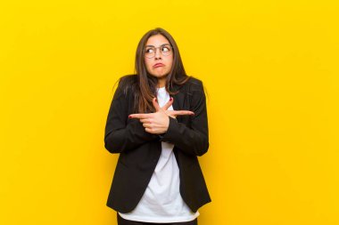 Kafası karışık, güvensiz ve turuncu duvara karşı kuşkuları olan genç ve güzel bir kadın.