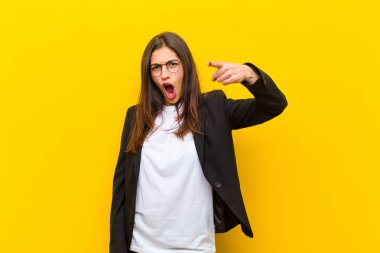 Genç ve güzel bir kadın kızgın agresif bir ifadeyle kameraya bakıyor. Turuncu duvara karşı öfkeli, çılgın bir patron gibi görünüyor.