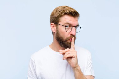 Genç, sarışın, yetişkin bir adam sessizlik ve sessizlik istiyor. Parmağını ağzının önüne uzatıp 