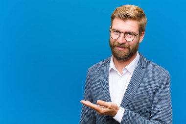 Neşeli bir şekilde gülümsüyor, mutlu hissediyor ve bir konsepti fotokopi uzayında avuç içiyle gösteriyor.