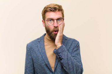 Sarışın genç işadamı şok olmuş ve şaşkınlık içinde ağzı açık bir şekilde yüz yüze inançsızlık içinde bekliyor.