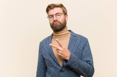 Genç sarışın iş adamı mutlu, pozitif ve başarılı hissediyor, göğsünde el yapımı V ile, zafer ya da barış gösteriyor.