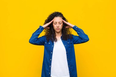 Genç ve güzel bir kadın. Yoğunlaşmış, düşünceli ve ilham verici görünüyor. Beyin fırtınası yapıyor ve elleri turuncu duvarda hayal ediyor.