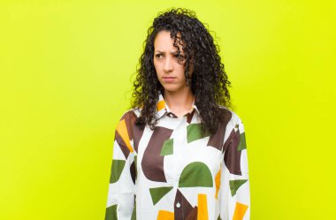 Genç, güzel bir kadın üzgün, üzgün ya da kızgın ve olumsuz bir tavır takınıyor. Krom anahtar duvarına karşı anlaşmazlık içinde.