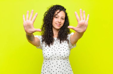 Genç ve güzel bir kadın gülümsüyor ve arkadaş canlısı görünüyor, onuncu ya da onuncu numarayı gösteriyor, elini öne uzatmış, kroma tuşuna karşı geriye doğru sayıyor.