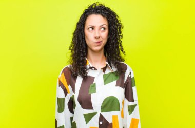 Genç ve güzel bir kadın şaşkın ve şaşkın görünüyor, merak ediyor ya da bir sorunu çözmeye çalışıyor ya da kroma tuşuna karşı düşünüyor.