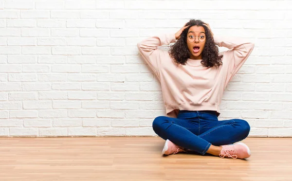 stock image young african american black woman with open mouth, looking horrified and shocked because of a terrible mistake, raising hands to head