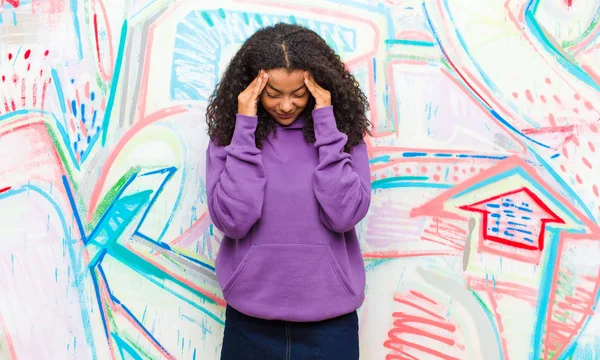 young pretty african american woman looking stressed and frustrated, working under pressure with a headache and troubled with problems against graffiti wall