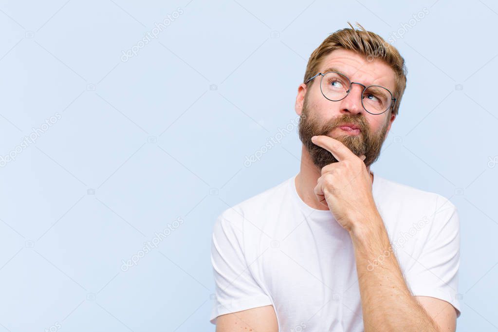 young blonde adult man thinking, feeling doubtful and confused, with different options, wondering which decision to make