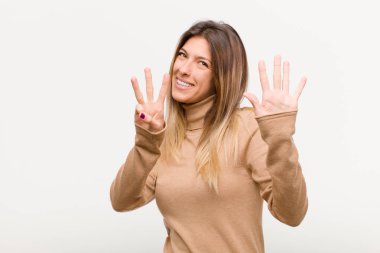 Genç, güzel bir kadın gülümsüyor ve arkadaş canlısı görünüyor. Sekiz ya da sekiz numarayı gösteriyor. Elleri önde, beyaz arka planda geriye doğru sayıyor.