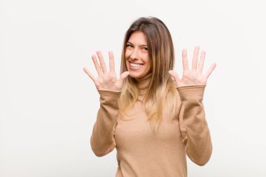 Genç ve güzel bir bayan gülümsüyor ve arkadaş canlısı görünüyor, onuncu ya da onuncu numarayı gösteriyor, beyaz arka planda geriye doğru sayıyor.