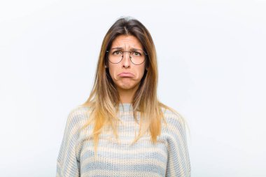 Genç ve güzel bir kadın üzgün ve mızmızlanıyor, mutsuz bir bakışla, ağlarken beyaz arka plana karşı olumsuz ve hayal kırıklığına uğramış bir tavırla