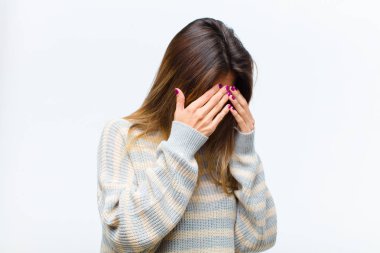 Genç, güzel bir kadın, üzgün, hayal kırıklığına uğramış bir bakışla gözlerini kapatıyor. Ağlıyor, beyaz arka plana yan bakıyor.