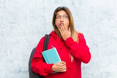 Genç, güzel bir öğrenci mutsuz, korkmuş ya da endişeli görünüyor ağzı sonuna kadar açık ve iki kulağını da elleriyle kapatıyor.