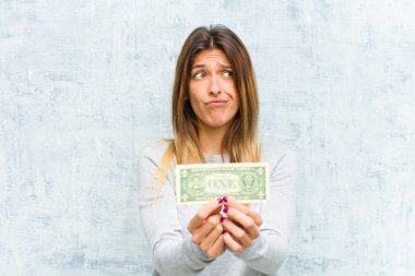Genç, güzel bir kadın. Banknotları grunge duvarına dayalı.