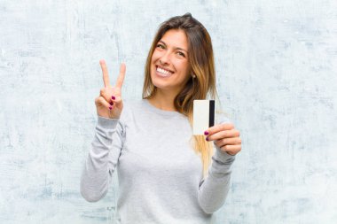 Genç ve güzel bir kadın kredi kartıyla grunge duvarına yaslanmış.