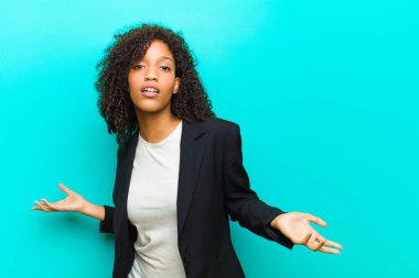 Genç siyahi kadın bilgisiz ve kafası karışmış hissediyor, hiçbir fikri yok, mavi duvara bakan aptal ya da aptal bir bakışla tamamen şaşkına dönmüş.