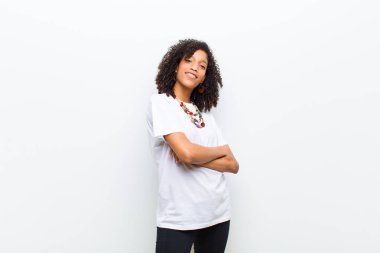 Genç, havalı, Afro-Amerikalı kadın kollarını kavuşturup mutlu bir şekilde gülüyor, rahat, pozitif ve tatmin edici bir pozla.