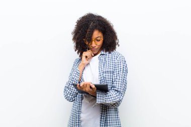 Beyaz duvara karşı akıllı tabletli genç, güzel siyah kadın.