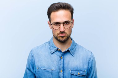 Genç yakışıklı adam üzgün ve mızmız, mutsuz bir bakışla, olumsuz ve hayal kırıklığına uğramış bir tavırla ağlıyor.