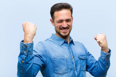 Genç yakışıklı adam zaferle bağırıyor. Heyecanlı, mutlu ve şaşırmış görünüyor. Kutlama yapıyor.