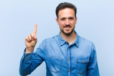 Genç yakışıklı adam neşeyle ve mutlulukla gülümsüyor, tek eliyle yukarıyı göstererek boşluğu kopyalıyor.