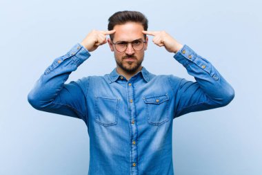 Ciddi ve konsantre görünümlü, beyin fırtınası yapan ve zorlu bir sorunu düşünen genç yakışıklı bir adam.