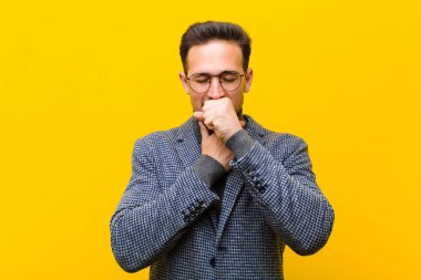 Gırtlağı ağrıyan ve grip belirtileri gösteren, ağzı turuncu duvara dayalı genç ve yakışıklı bir adam.