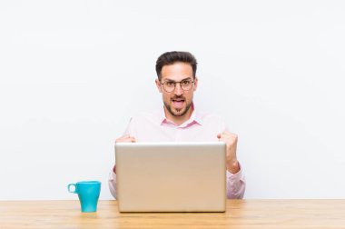 Genç yakışıklı iş adamı şok olmuş, heyecanlı ve mutlu hissediyor, gülüyor ve başarıyı kutluyor,!