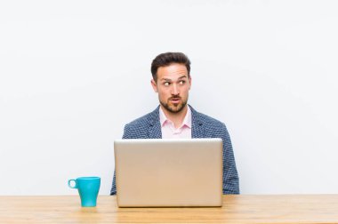 Genç yakışıklı iş adamı şaşkın, mutlu, şaşkın ve şaşırmış hissediyor, ağzı açık bir şekilde yana bakıyor.