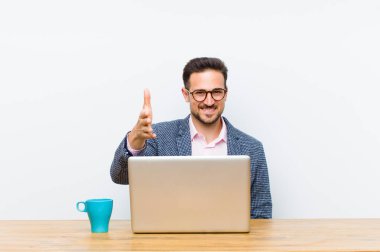 Genç yakışıklı iş adamı gülümsüyor, mutlu, kendinden emin ve arkadaş canlısı görünüyor, bir anlaşmaya varmak için el sıkışıyor, işbirliği yapıyor.