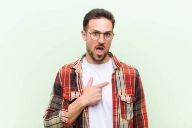 Şok olmuş ve ağzı açık, kendini işaret eden genç yakışıklı bir adam.