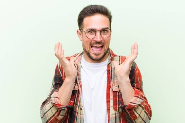 Genç ve yakışıklı bir adam beklenmedik bir sürpriz yüzünden şaşkın ve heyecanlı, güler yüzlü, şaşkın ve mutlu hissediyor.