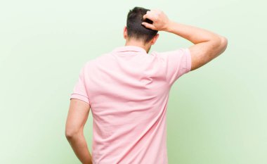 Genç yakışıklı bir adam bilgisiz ve kafası karışık hissediyor, bir çözüm düşünüyor, eli kalçasında, diğeri kafasında, dikiz aynasından.