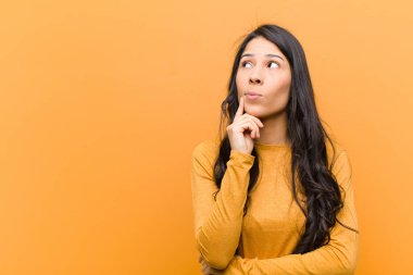 Genç, güzel, İspanyol bir kadın. Yoğunlaşmış bakışları var. Şüpheli bir ifadeyle, yukarı ve yana kahverengi duvara bakıyor.