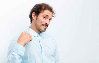 Genç yakışıklı adam kibirli, başarılı, pozitif ve gururlu görünüyor, kendini beyaz duvara gösteriyor.
