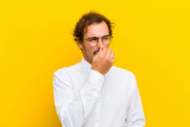 Genç yakışıklı adam iğreniyor, burnundan tutup turuncu duvardaki pis ve nahoş kokuyu koklamaktan kaçınıyor.