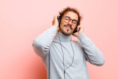 Pembe düz duvara karşı kulaklıklı genç yakışıklı adam.