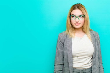 Genç, güzel, sarışın kadın merak ediyor, mutlu düşünceler ve fikirler düşünüyor, hayal kuruyor, düz duvara karşı uzayı kopyalamaya çalışıyor.