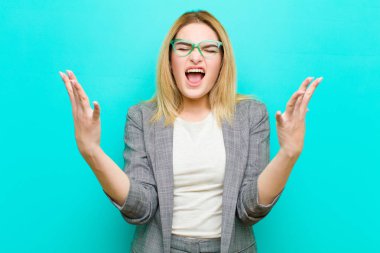 Genç, güzel, sarışın bir kadın öfkeyle bağırıyor, stresli ve elleri havada, neden düz duvara yaslandığımı söylüyor.