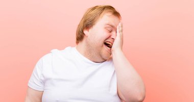 Genç, iri yarı bir adam uykulu, sıkılmış ve esniyor. Başı ağrıyor ve yüzünün yarısı pembe duvarla kaplı.