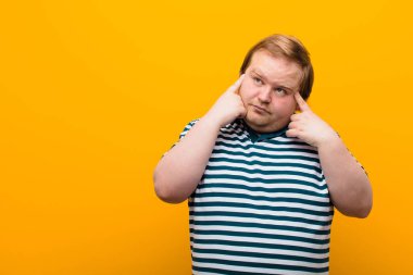 Genç, iri yarı bir adam konsantre olmuş ve bir fikir üzerinde kafa yoruyor. Turuncu duvardaki bir soruna ya da meydan okumaya çözüm bulmayı hayal ediyor.