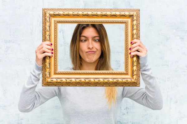 young pretty woman with a baroque frame against grunge wall