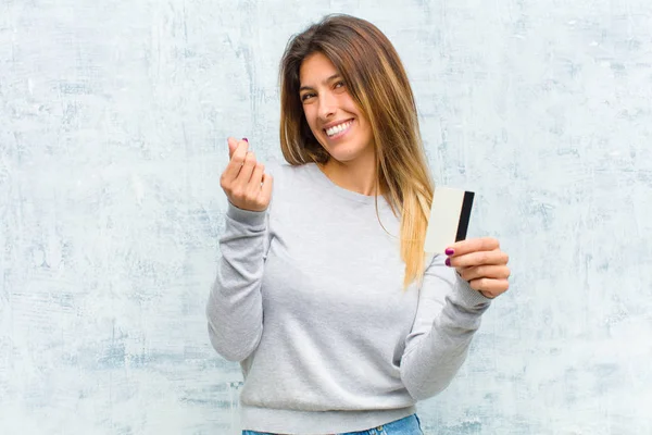 young pretty woman with a credit card against grunge wall