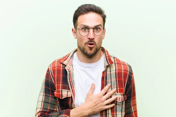 Joven Hombre Guapo Sintiéndose Sorprendido Sorprendido Sonriendo Tomando Mano Corazón — Foto de Stock