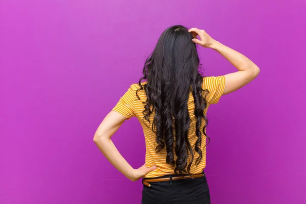 年轻漂亮的拉丁女人感到茫然和困惑 想出了一个解决办法 双手放在髋部和其他部位 背向紫色的墙壁 — 图库照片