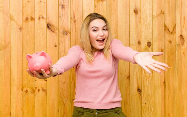 Joven Bonita Mujer Rubia Con Una Alcancía Contra Pared Madera — Foto de Stock