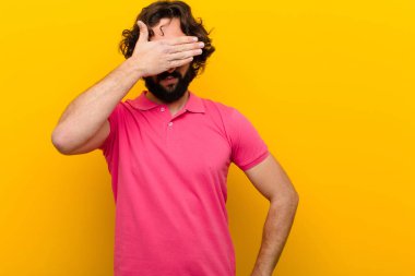 Genç, deli bir adam gözlerini kapatıyor. Korkmuş ya da endişeli hissediyor, merak ediyor ya da turuncu duvara karşı bir sürpriz bekliyor.