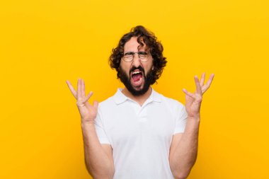Genç çılgın adam öfkeyle bağırıyor, stresli hissediyor ve ellerini havaya kaldırıp neden sarı duvara yaslandığımı söylüyor.